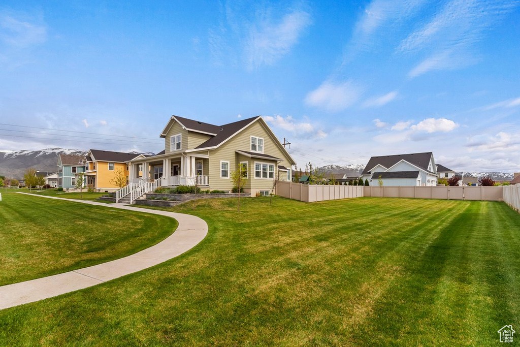 Rear view of property with fence, a lawn, a porch, and a residential view