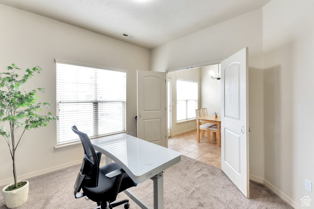 Office area featuring baseboards, visible vents, light colored carpet, and a wealth of natural light