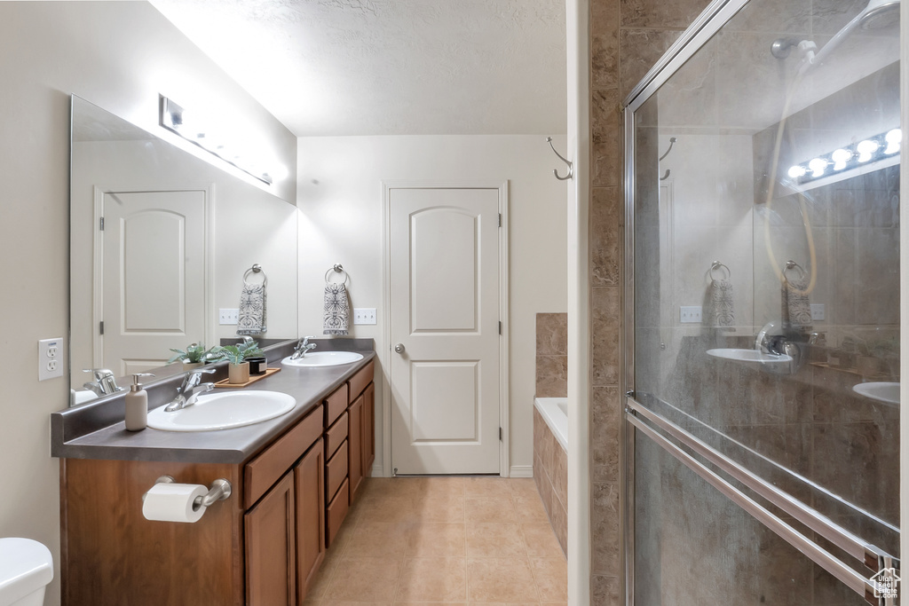 Full bathroom with tile patterned floors, a sink, double vanity, and tiled shower