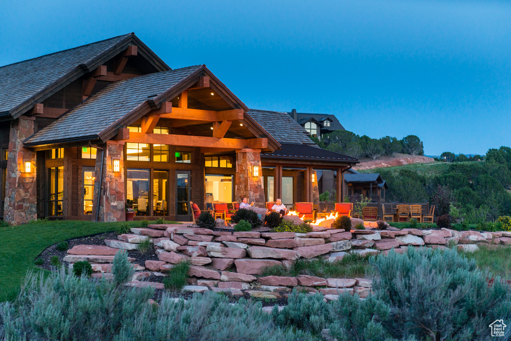Rear view of house featuring stone siding and an outdoor fire pit