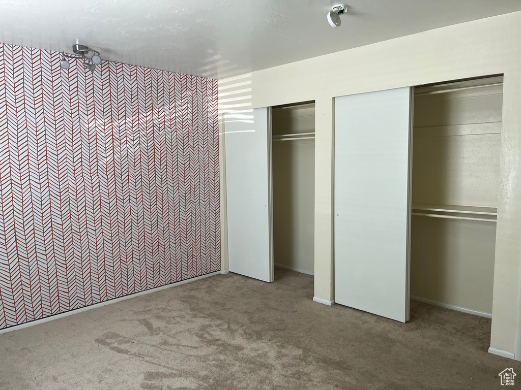 Unfurnished bedroom with baseboards, carpet, and multiple closets