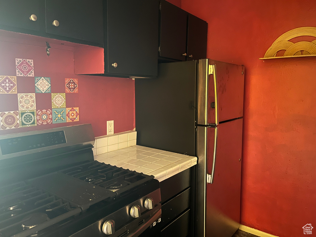 Kitchen featuring dark cabinets, stainless steel appliances, and tile countertops