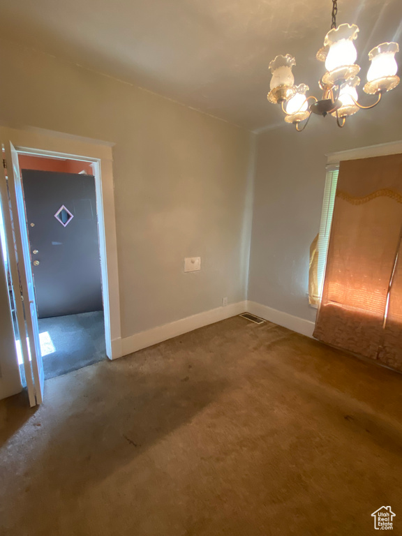Unfurnished room featuring baseboards, a chandelier, and carpet
