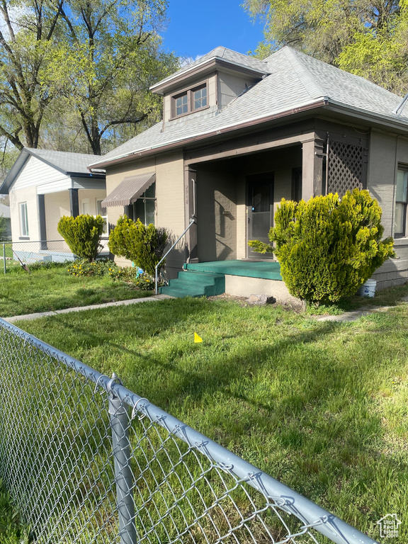Exterior space featuring brick siding, a yard, a shingled roof, and fence private yard