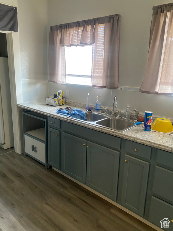 Kitchen with green cabinetry, dark wood-style floors, light countertops, a sink, and refrigerator