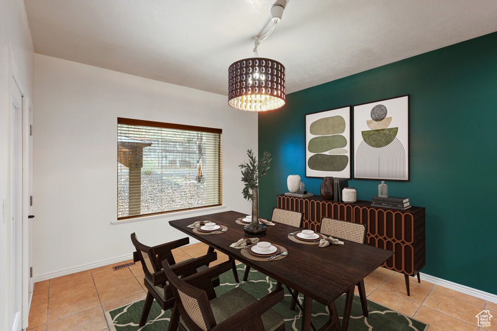 Dining area featuring a chandelier, light tile patterned flooring, and baseboards