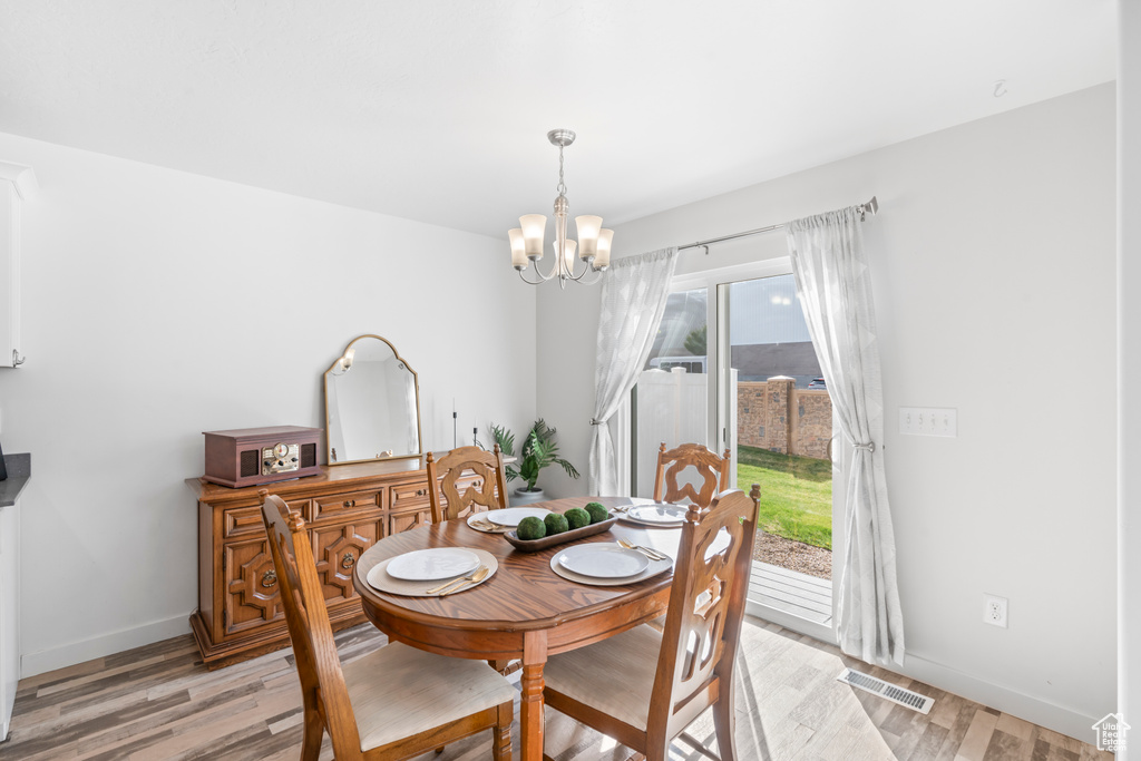 Dining space featuring light wood-style floors, visible vents, baseboards, and a notable chandelier