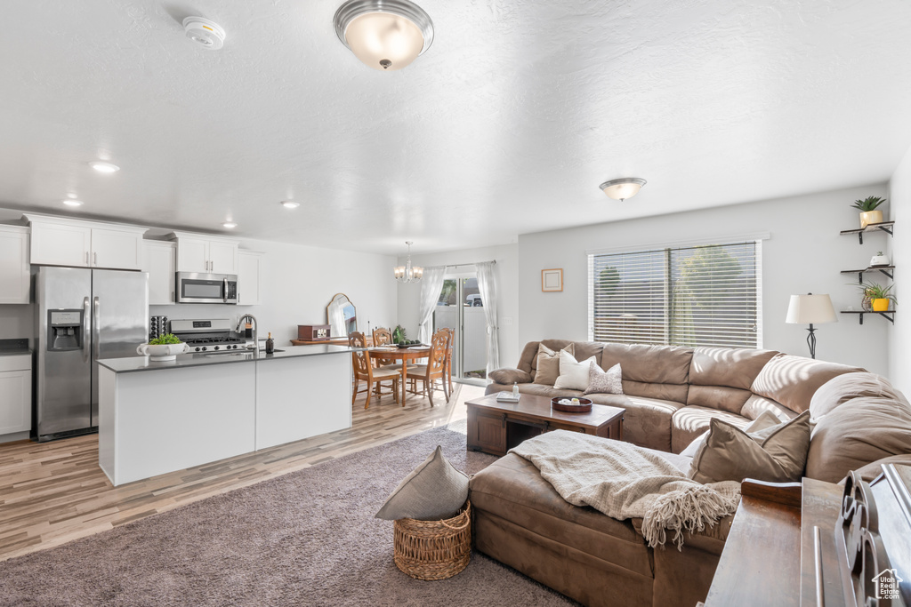 Living room with recessed lighting, a chandelier, and light wood-type flooring