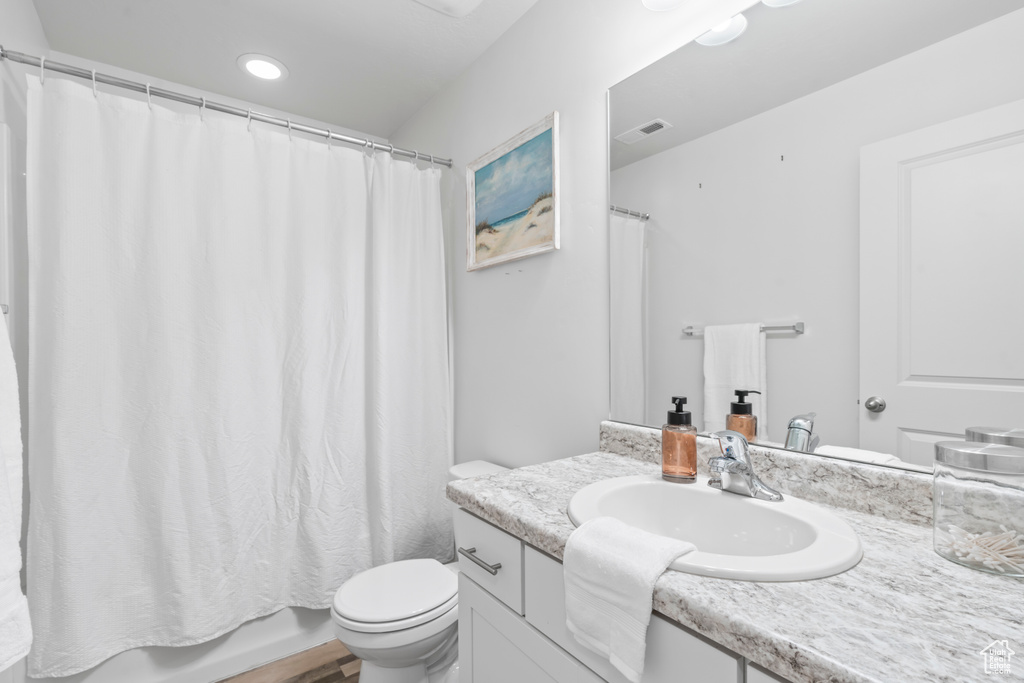 Bathroom featuring toilet, visible vents, recessed lighting, shower / tub combo with curtain, and vanity