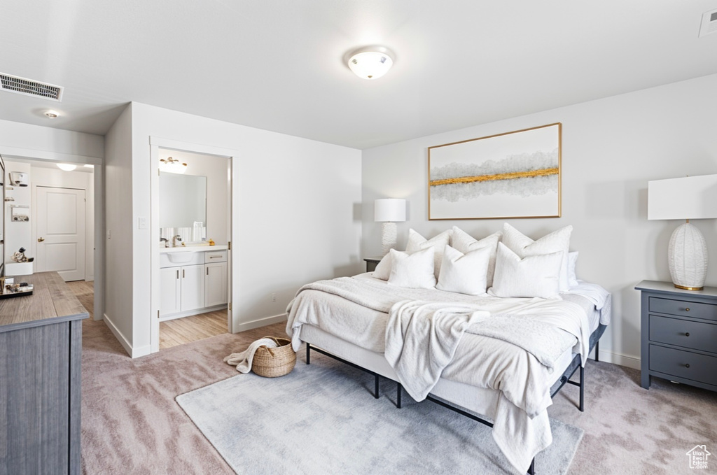 Bedroom with light carpet, baseboards, a sink, and connected bathroom