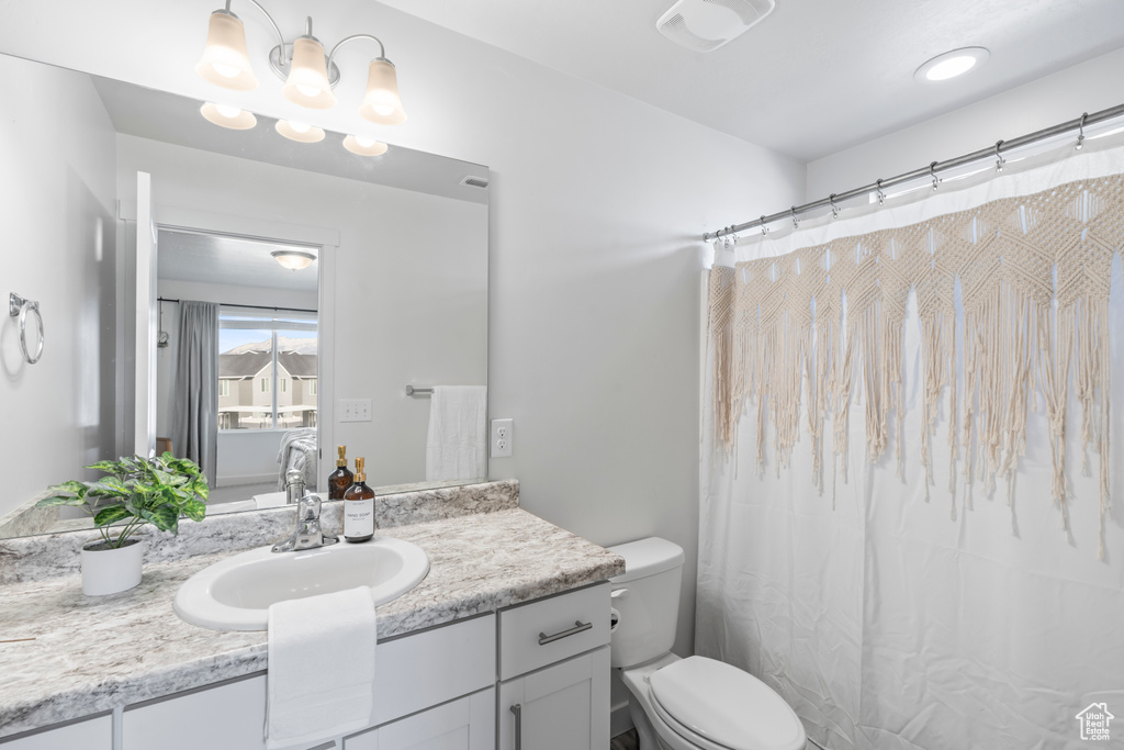 Bathroom featuring toilet, vanity, and a shower with curtain