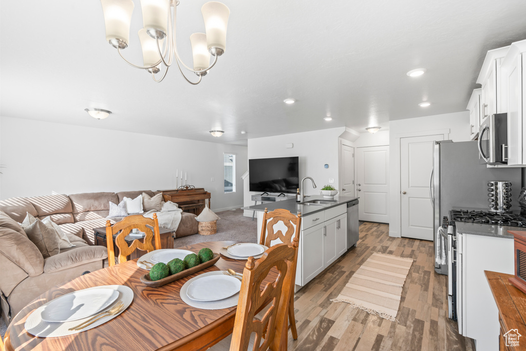 Dining room featuring baseboards, a chandelier, light wood-style floors, and recessed lighting