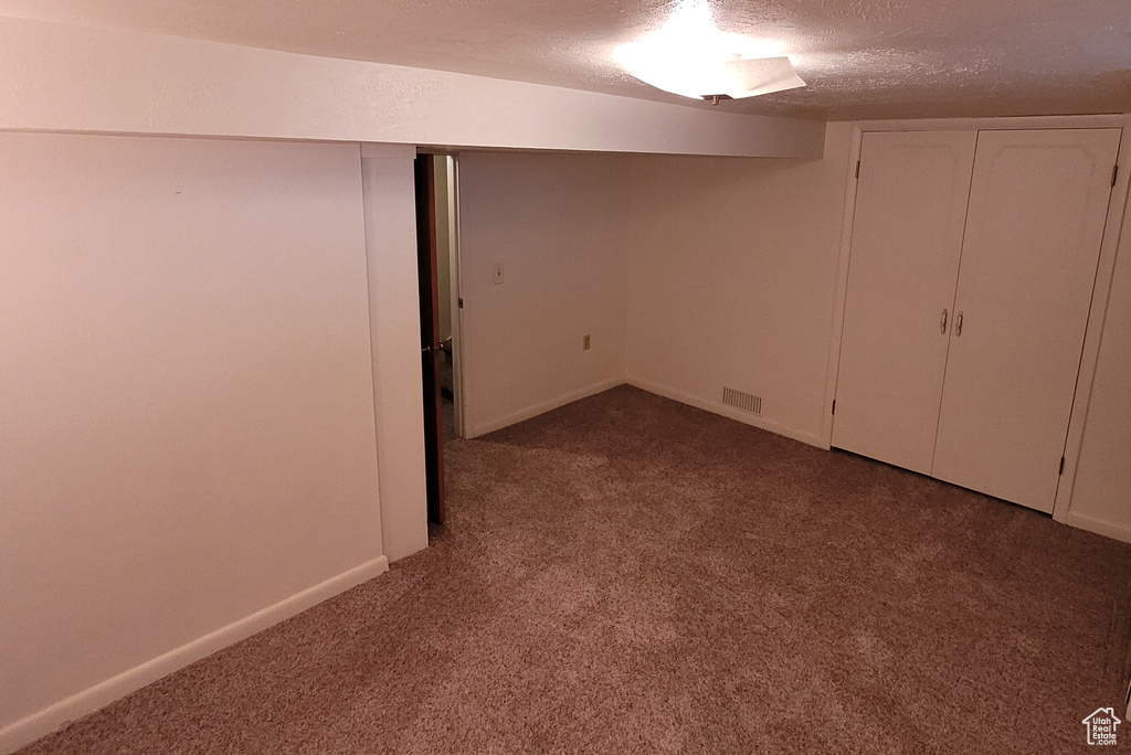 Finished basement with carpet flooring, a textured ceiling, and baseboards