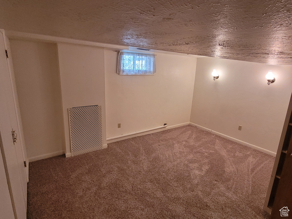 Basement featuring carpet floors, a textured ceiling, and baseboards