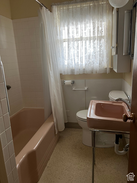 Bathroom with shower / bath combo with shower curtain, toilet, and a sink