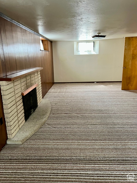 Below grade area with carpet floors, wood walls, and a brick fireplace