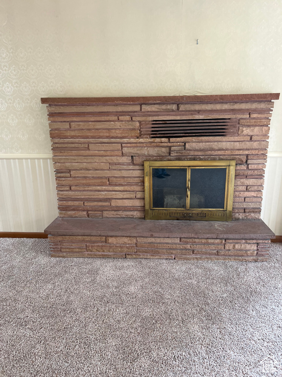 Details featuring wainscoting, wallpapered walls, a glass covered fireplace, and carpet floors
