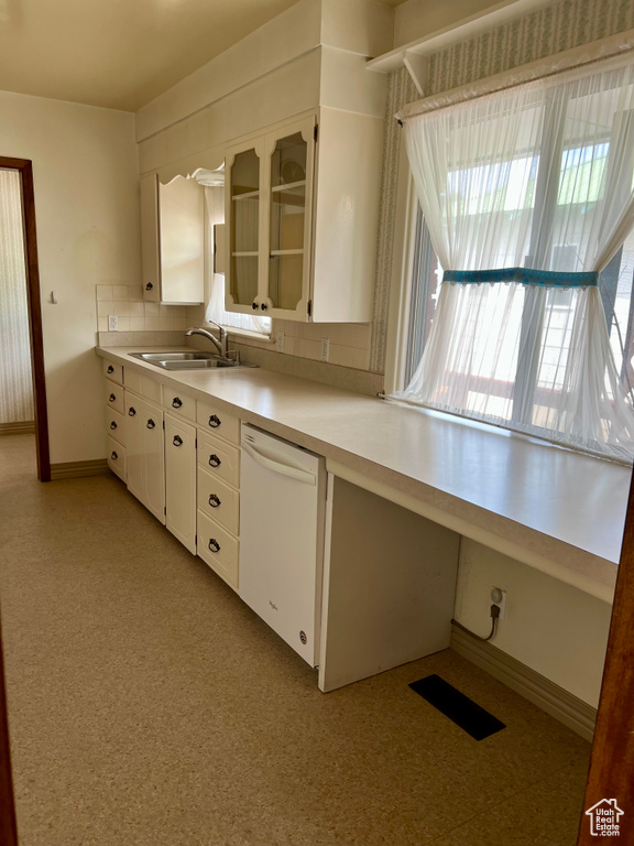Kitchen with a sink, baseboards, white cabinetry, dishwasher, and light countertops