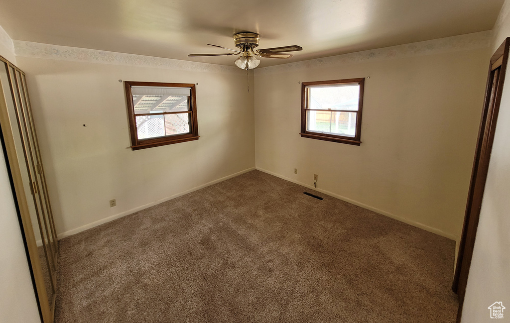 Carpeted spare room featuring ceiling fan and baseboards