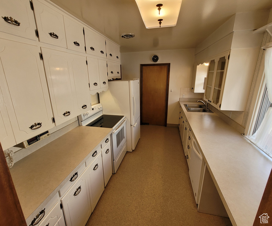 Kitchen with white appliances, a sink, white cabinetry, light countertops, and glass insert cabinets