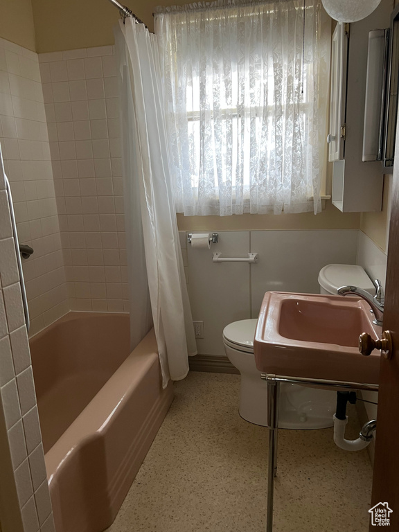 Full bathroom with toilet, shower / tub combo with curtain, and a sink
