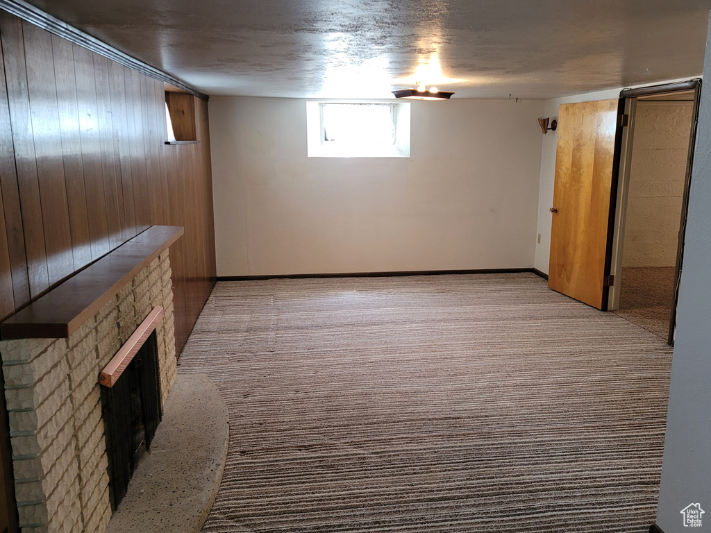 Basement featuring a stone fireplace, light carpet, and baseboards