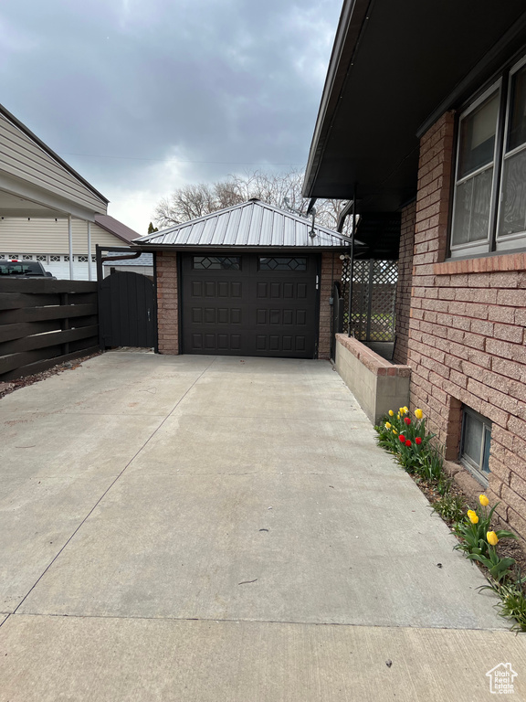 View of side of home featuring fence, an outbuilding, brick siding, and a detached garage