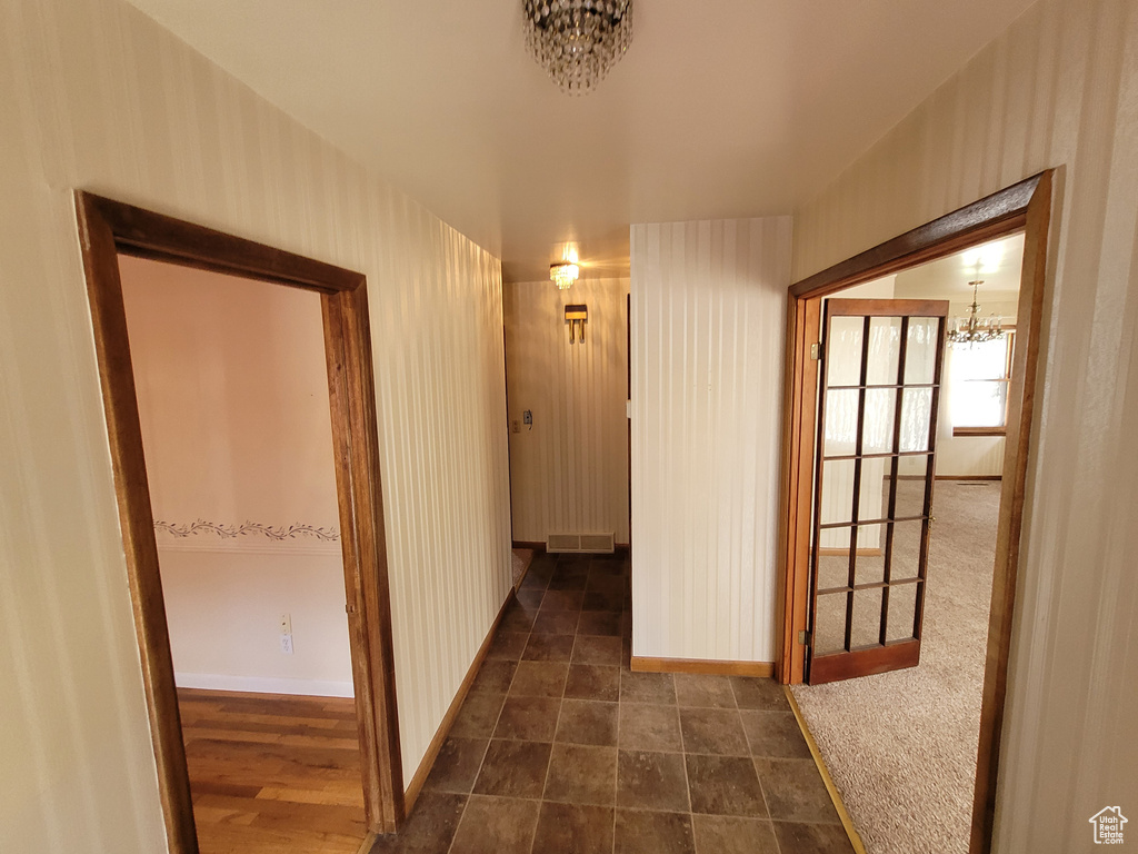 Hallway featuring a chandelier and baseboards