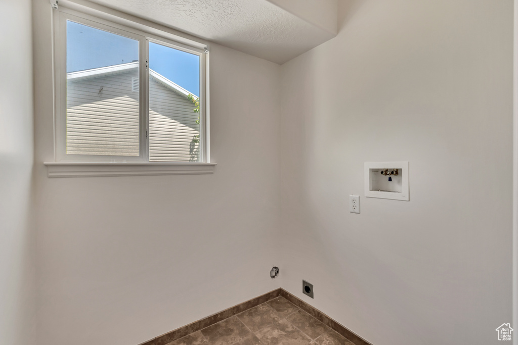 Washroom with a textured ceiling, baseboards, hookup for a washing machine, hookup for an electric dryer, and laundry area