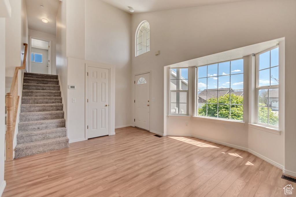 Foyer entrance with stairway, baseboards, visible vents, and light wood-style floors