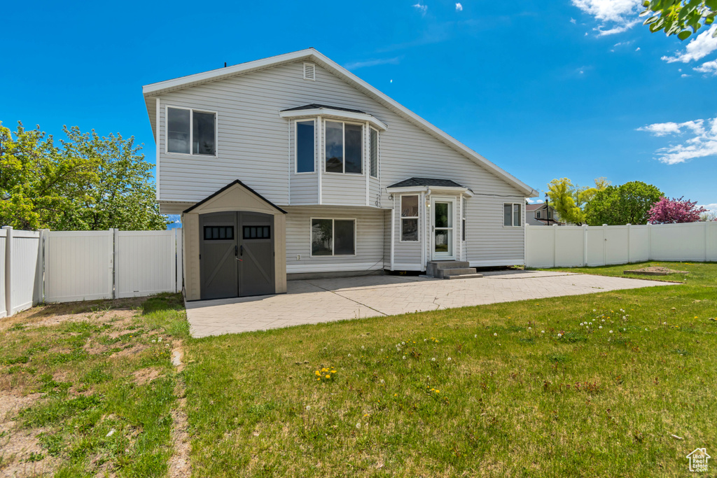 Back of house featuring a yard, entry steps, a patio, and a shed