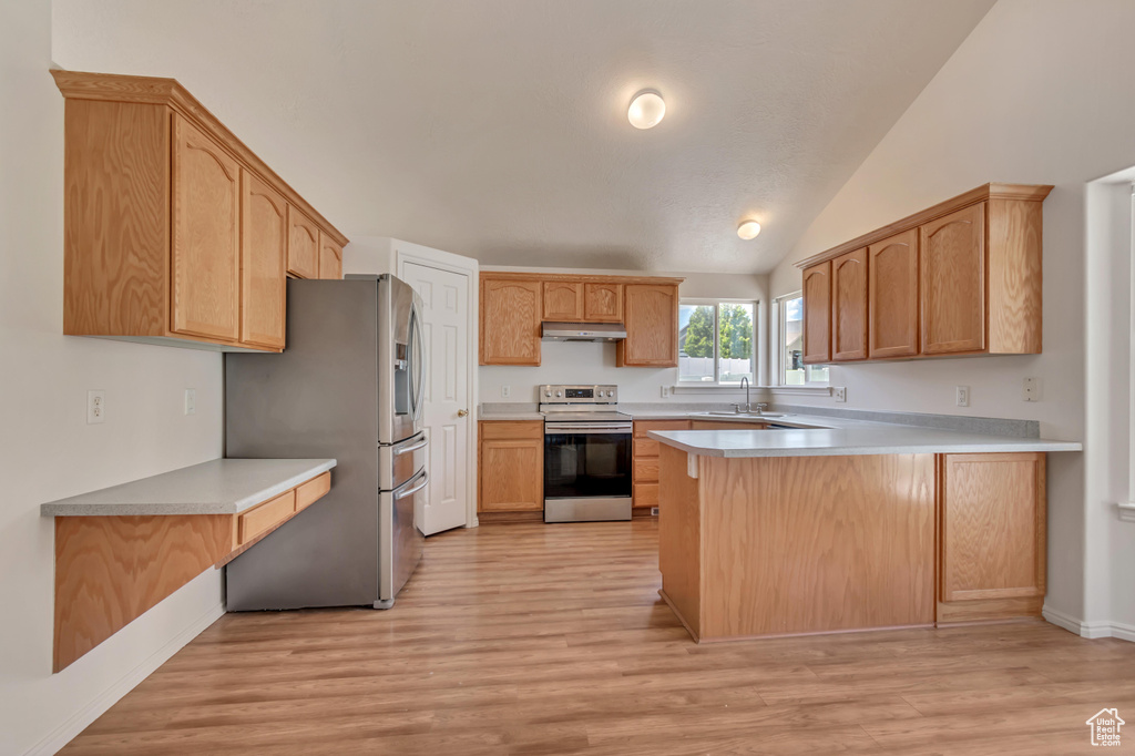 Kitchen featuring appliances with stainless steel finishes, under cabinet range hood, a peninsula, light countertops, and light wood-type flooring