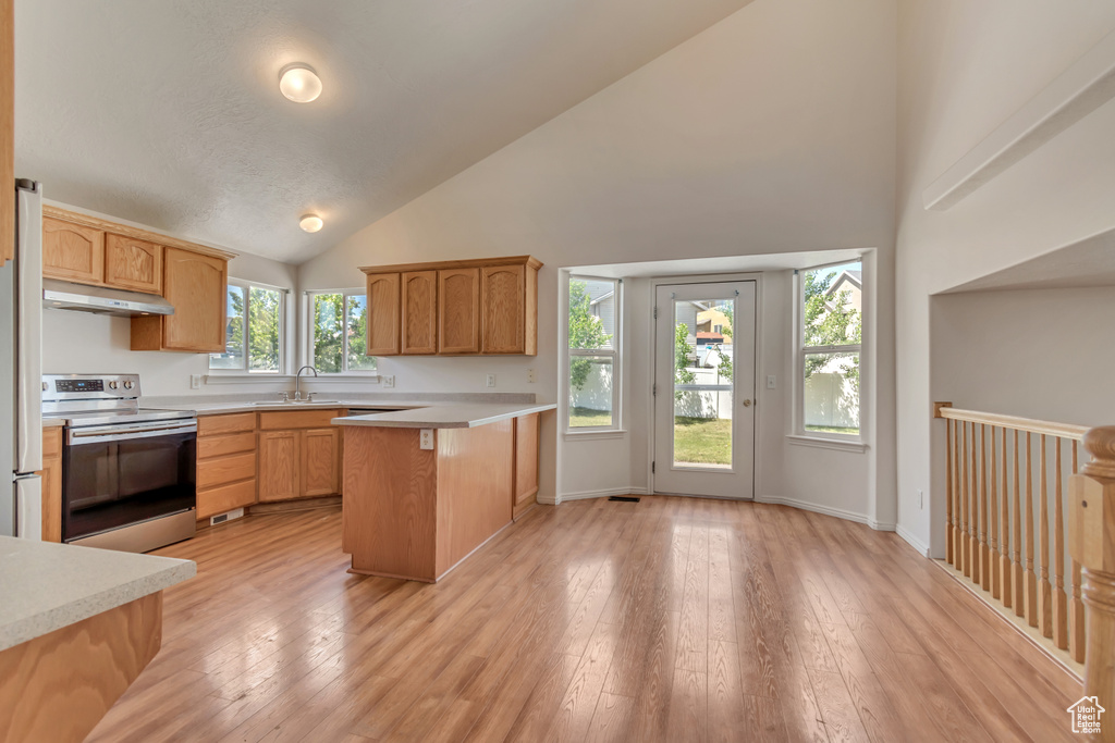 Kitchen with a sink, high vaulted ceiling, under cabinet range hood, light countertops, and stainless steel electric range oven