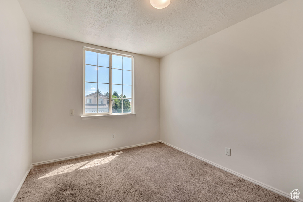 Carpeted empty room with a textured ceiling, visible vents, and baseboards