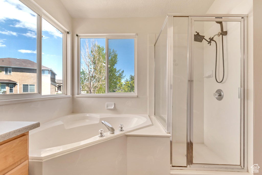 Bathroom with a bath, a wealth of natural light, and a shower stall