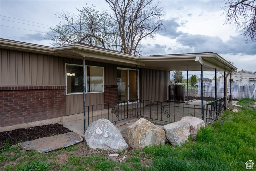 View of exterior entry featuring brick siding, board and batten siding, and fence