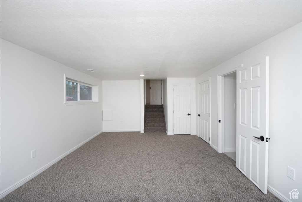 Below grade area featuring stairway, baseboards, and carpet