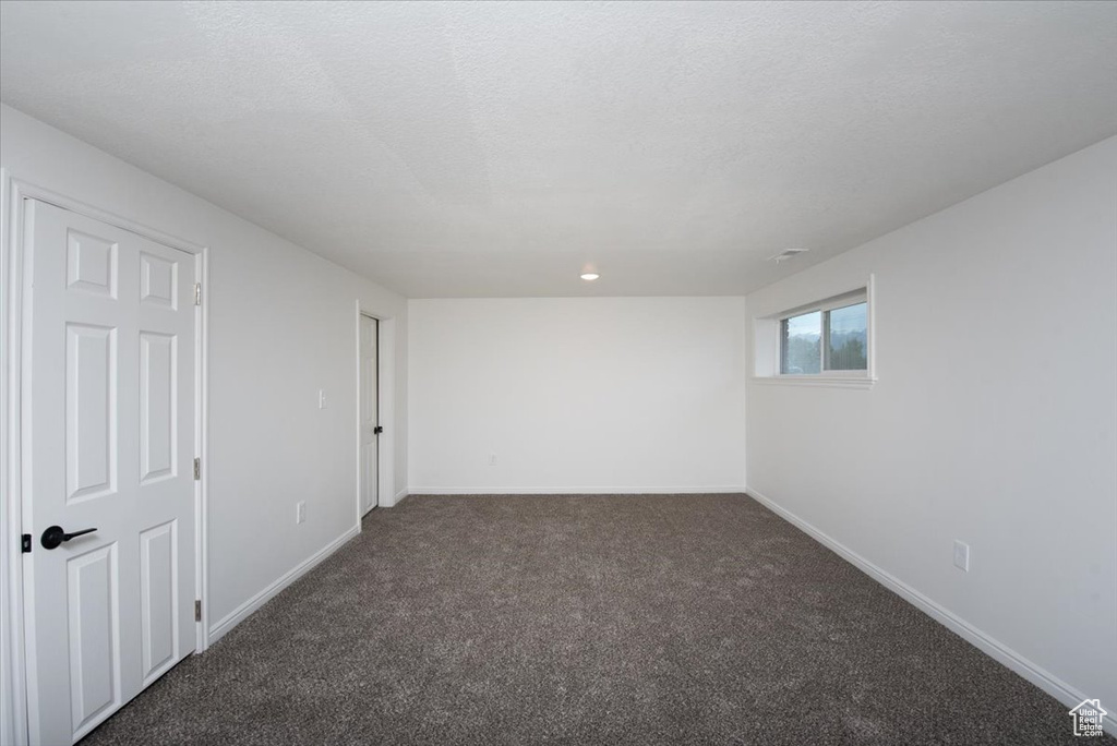 Unfurnished room featuring baseboards and dark colored carpet