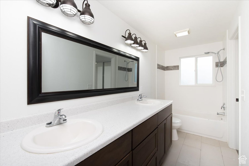 Bathroom featuring double vanity, a sink, shower / bath combination, and toilet