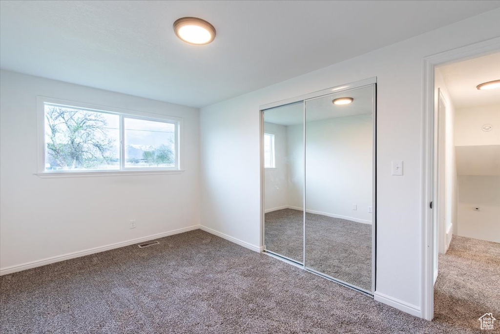 Unfurnished bedroom with visible vents, carpet, baseboards, and a closet