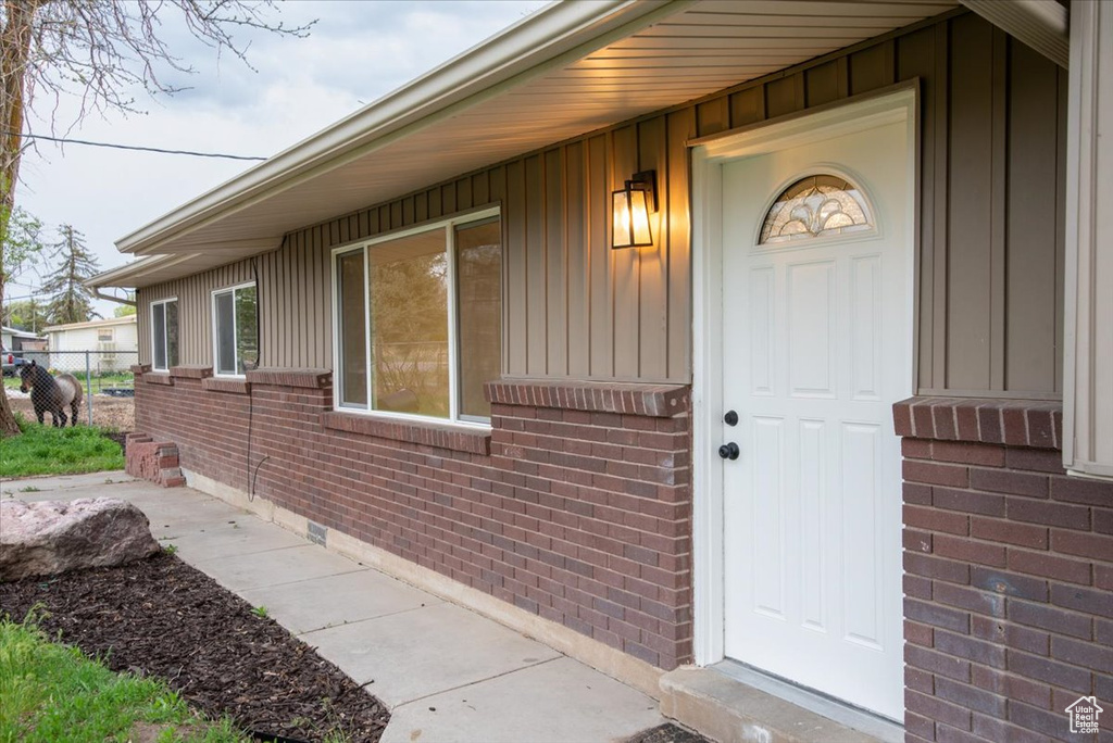 Entrance to property with fence, board and batten siding, and brick siding