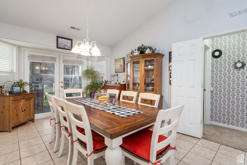 Dining room featuring high vaulted ceiling, a notable chandelier, visible vents, and light tile patterned floors