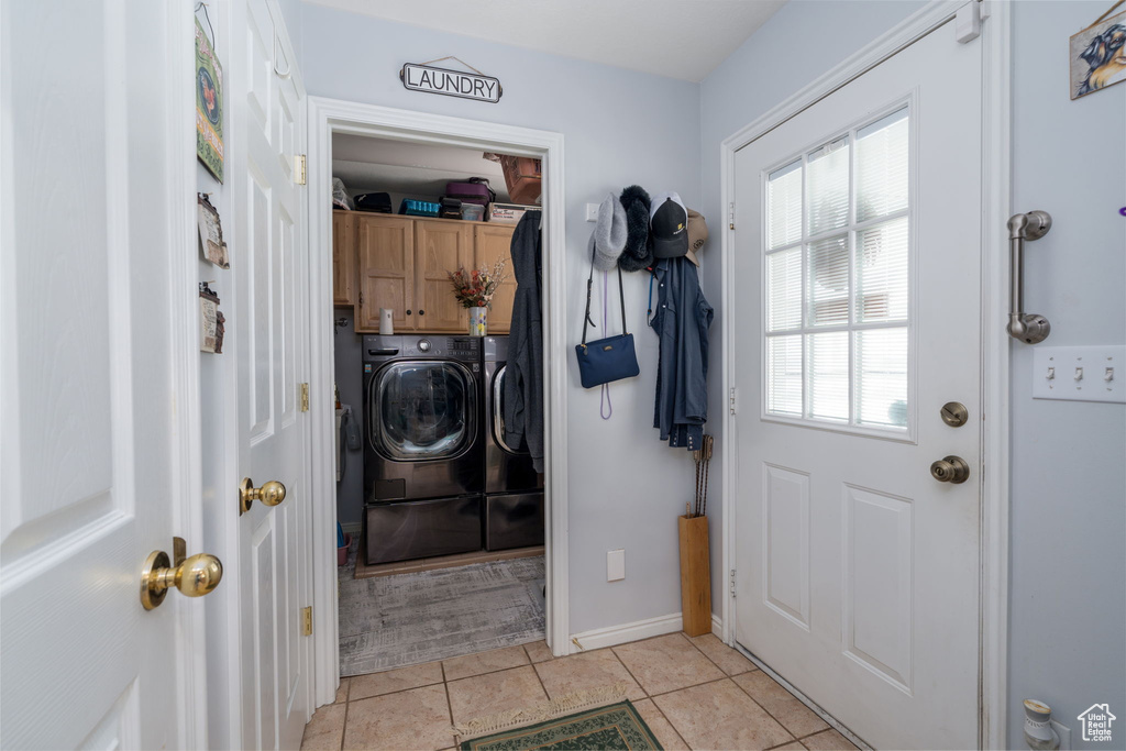 Interior space with washing machine and clothes dryer, cabinet space, light tile patterned flooring, and baseboards