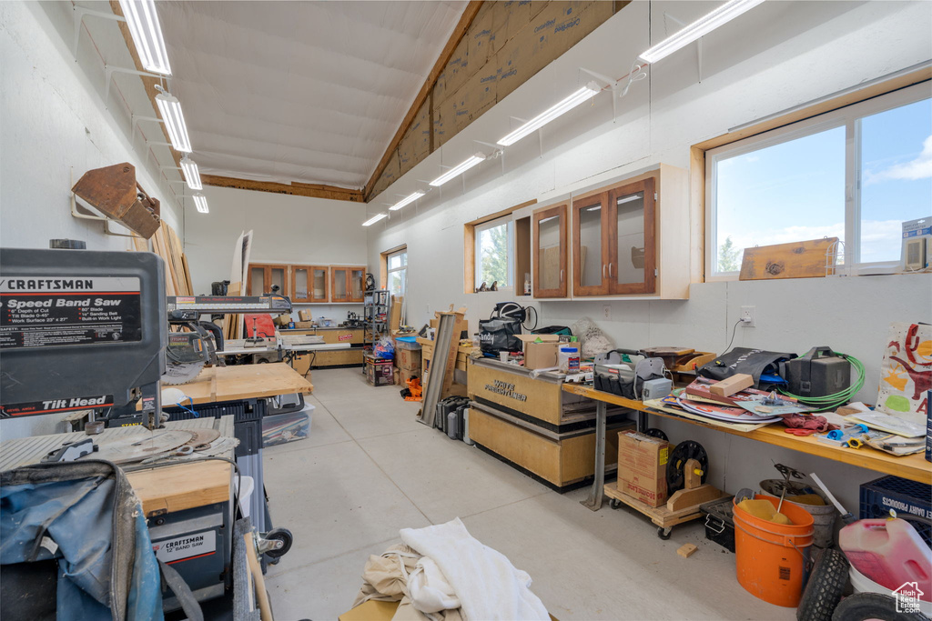 Miscellaneous room with concrete floors, a workshop area, and high vaulted ceiling