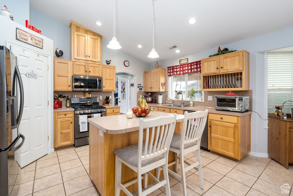 Kitchen with backsplash, appliances with stainless steel finishes, and light brown cabinets