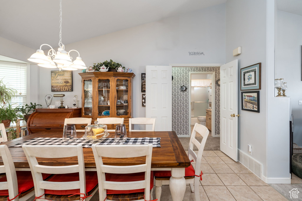 Dining room featuring high vaulted ceiling, baseboards, an inviting chandelier, and light tile patterned floors