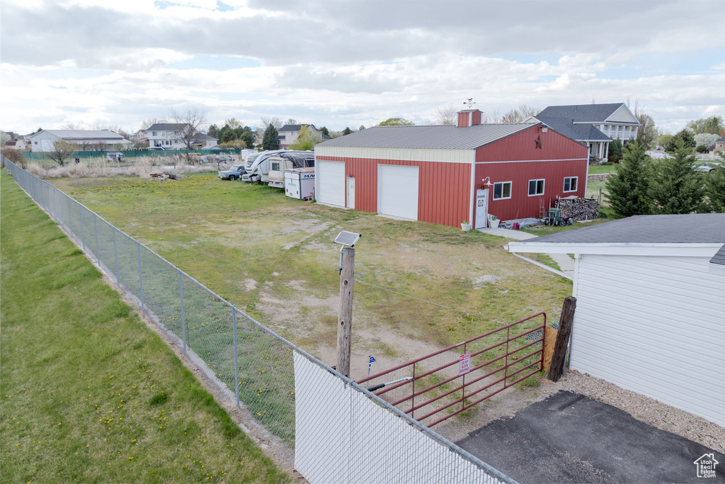 View of yard featuring fence, an outbuilding, a pole building, and a garage
