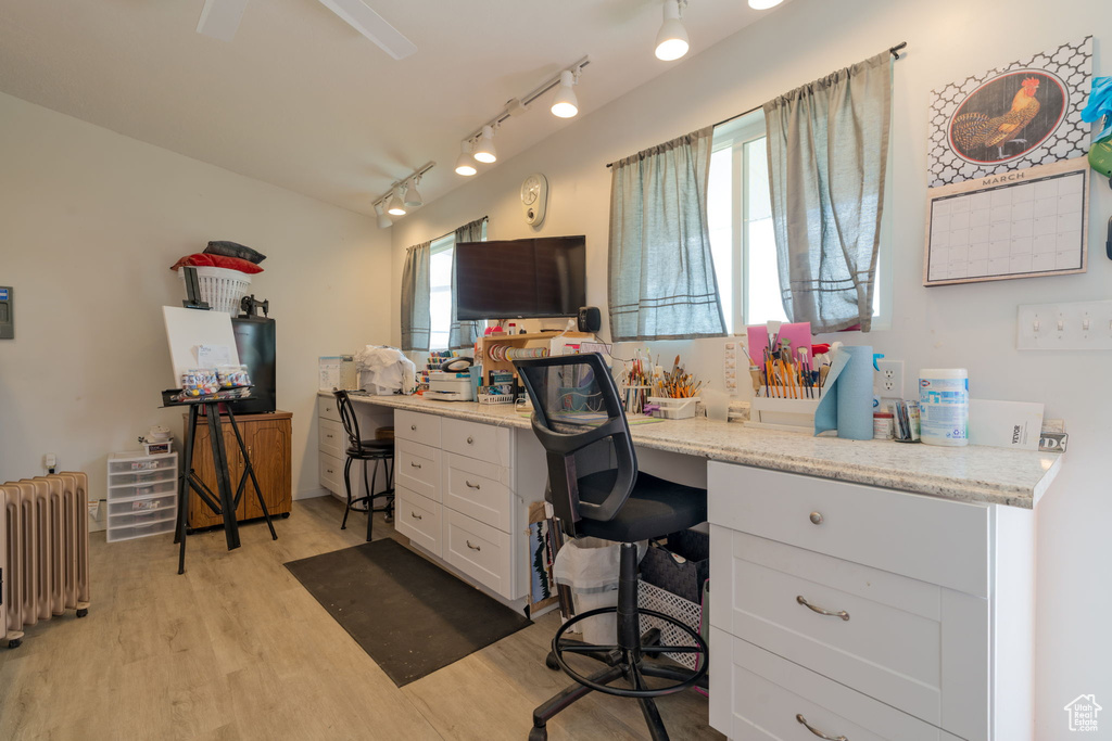Home office with radiator heating unit, track lighting, and light wood finished floors