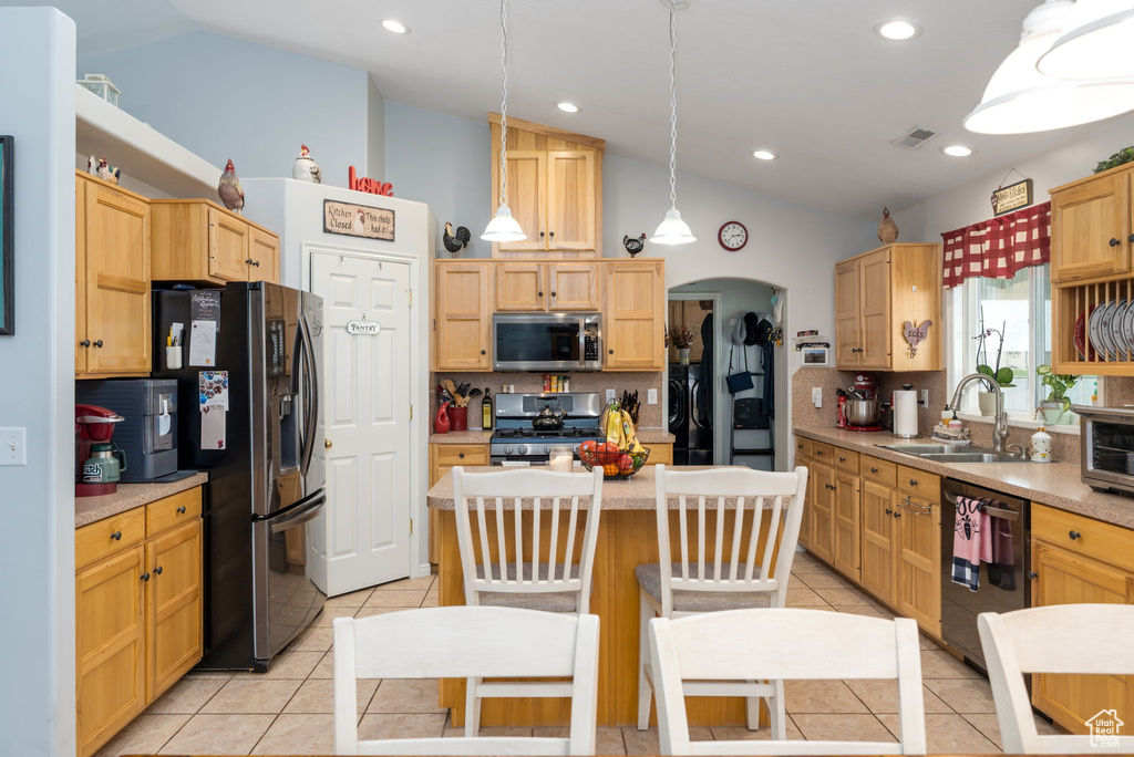 Kitchen featuring a sink, decorative backsplash, light tile patterned floors, lofted ceiling, and appliances with stainless steel finishes