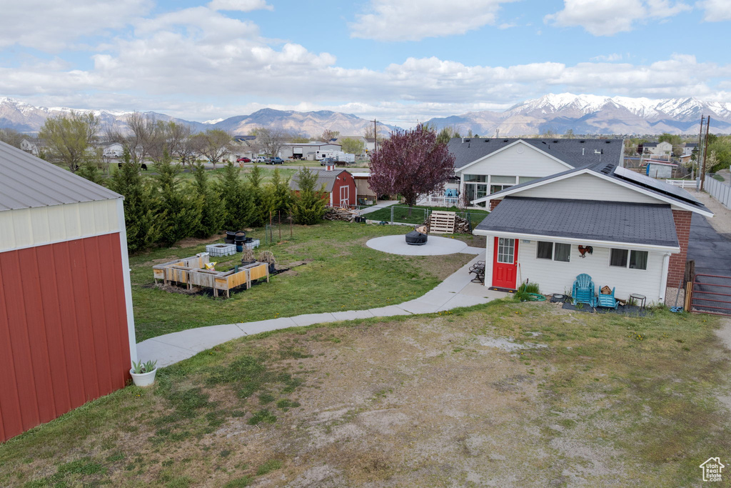 View of yard featuring a storage unit, an outdoor structure, a mountain view, and an outdoor fire pit